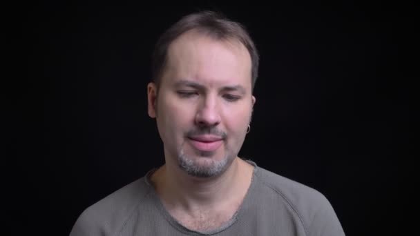 Portret van middelbare leeftijd geconcentreerd Kaukasische man met earring draaien hoofd negatief in camera op zwarte achtergrond. — Stockvideo