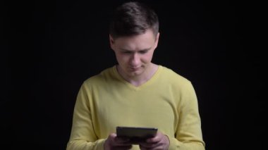 Sarı kazaklı gülümseyerek tablet siyah arka plan üzerinde içine izlerken orta yaşlı beyaz adam portresi.