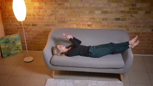Gros plan top shoot portrait de jeune étudiante utilisant le téléphone et couchée sur le canapé se reposant à l'intérieur à la maison confortable — Video