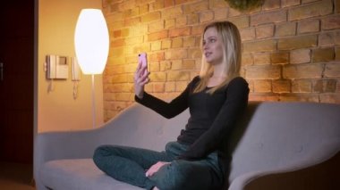 Portre yan görüntülemek video aramasý telefonda olması ve rahat evde kapalı kanepede otururken gülümseyen genç güzel kız öğrencinin portresi