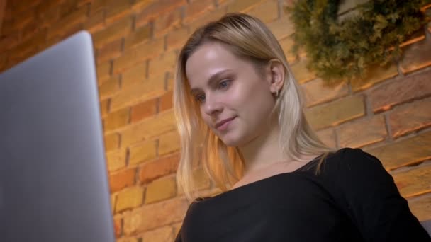 Closeup schieten van jonge mooie huisvrouw met behulp van de laptop en zittend op de Bank gezellig thuis binnenshuis — Stockvideo