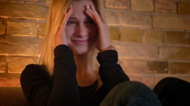 Genç güzel ev hanımı bir korku filmi korkmaya TV izlerken portre çekimleri ve kapalı rahat evde kanepede otururken yüzünü gizleme