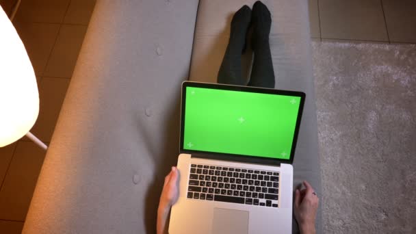 Sesión de primer plano de una joven blogger usando las redes sociales mientras escribe en el portátil con pantalla verde. Las niñas piernas en calcetines lindos en el sofá acogedor — Vídeos de Stock