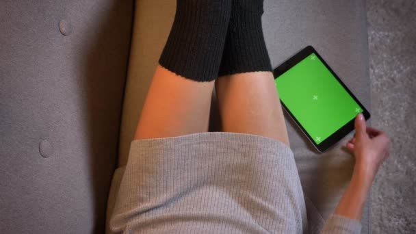 Крупный план молодой сексуальной красоты блоггер социальных сетей с использованием планшета с зеленым экраном. Женские бёдра в соблазнительных носках на диване — стоковое видео