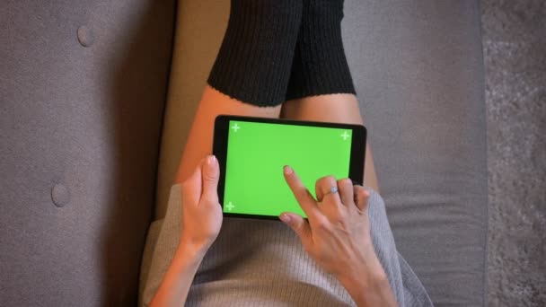 Gros plan sur le blogueur de mode séduisante sur les médias sociaux en utilisant la tablette avec écran vert. Femmes cuisses en chaussettes mignonnes sur le canapé — Video