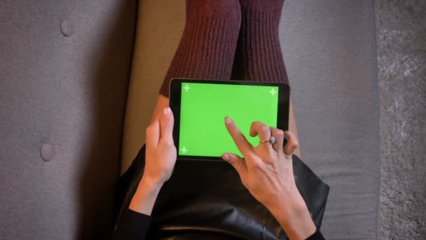 緑色の画面でタブレットを使用して魅惑的なファッション ソーシャル メディア インフルエンサーのクローズ アップを撮影します。梨花かわいいニットの靴下とソファにレザー スカート太もも — ストック動画