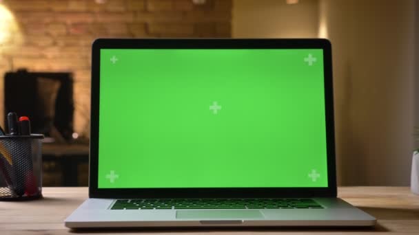 Primer plano de la computadora portátil con pantalla verde en el escritorio en la oficina en el interior con el hombre de negocios en el fondo borroso — Vídeos de Stock
