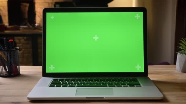 特写镜头拍摄的相机移动周围的笔记本电脑与绿色色度键屏幕上的广告在桌子上的办公室在室内 — 图库视频影像