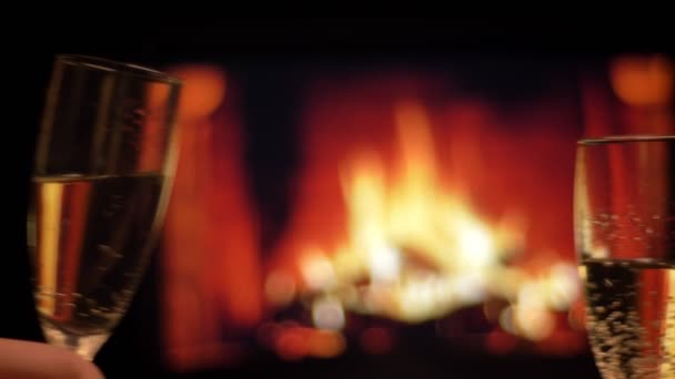 Sesión de cerca de dos manos de pareja enamorada tintineo vasos llenos de champán celebrando una cita nocturna con acogedora chimenea caliente en el fondo interior — Vídeos de Stock