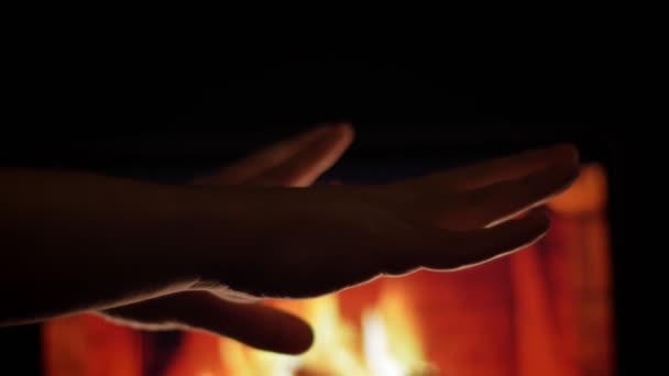 Vista lateral de primer plano brote de manos masculinas frotando y calentando frente a la chimenea caliente y la quema de madera en el interior de un acogedor apartamento — Vídeos de Stock