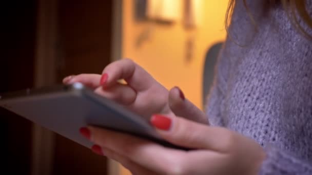 Gros plan pousse des mains féminines tapant sur la tablette à la maison confortable à l'intérieur 