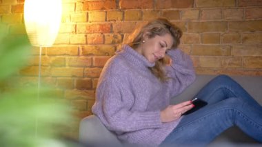 Portre profil ateş yetişkin beyaz sarışın kadın tablet kapalı rahat bir daire içinde kanepede otururken kullanma