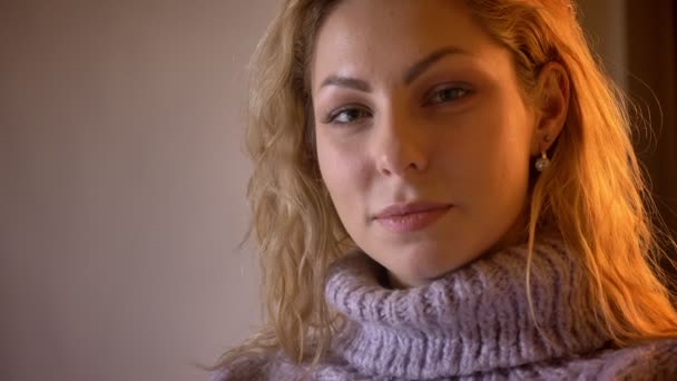 Close-up retrato de adulto muito caucasiano loira fêmea olhando para a câmera e sorrindo sedutoramente em um aconchegante apartamento — Vídeo de Stock
