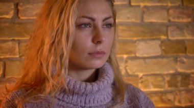 Closeup çekim yetişkin beyaz sarışın kadın kapalı, rahat ev kanepede otururken bir fincan sıcak çay tutan baktılar yüz ifadesi ile Tv izleme
