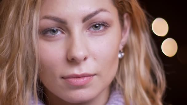 Closeup schieten van volwassen aantrekkelijke blonde Kaukasische vrouw zoekt rechte camera met bokeh achtergrond — Stockvideo