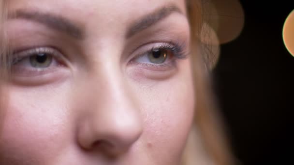 Closeup portret van volwassen aantrekkelijke blonde Kaukasische vrouwelijke op zoek voorwaarts openen en sluiten van haar ogen met bokeh achtergrond — Stockvideo