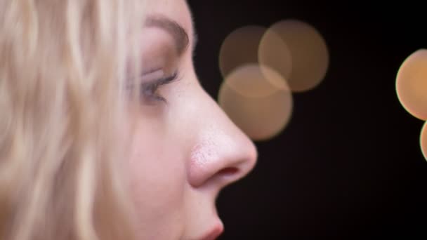 Nahaufnahme Seitenansicht Porträt von erwachsenen attraktiven Blondine kaukasischen weiblichen Hinwendung zur Kamera Blick direkt in die Kamera mit Bokeh-Hintergrund — Stockvideo