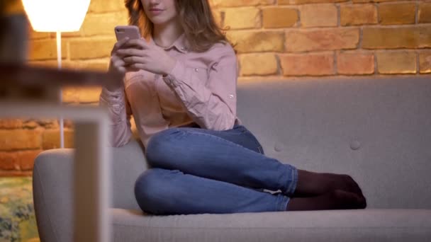 Dolly lövés alulról tetején a fiatal vonzó tizenéves lány figyeli okostelefon otthonos otthon hangulatát — Stock videók