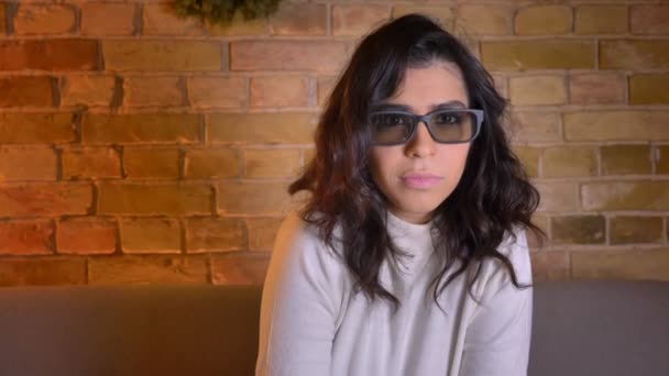 Joven mujer morena caucásica en gafas 3d ve película de terror y se reclina en el sofá en el momento inesperado en casa . — Vídeos de Stock
