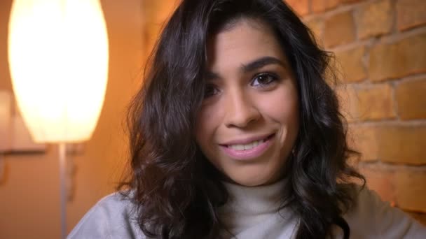 Close-up retrato de mulher morena caucasiana feliz levanta os olhos e sorrindo para a câmera em ambiente acolhedor casa . — Vídeo de Stock