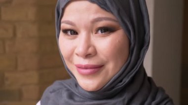 Tesettür kamera bakıyor ve işyerinde mutlu kapalı gülümsüyor yetişkin Müslüman kadın çalışanın closeup ateş