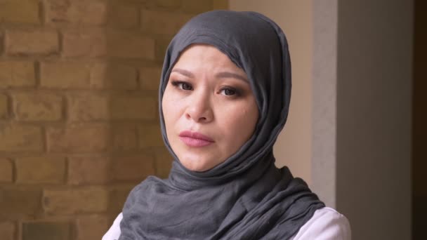 Närbild skjuta av vuxna muslimska kvinnliga anställd i hijab tittar på kamera i kontemplation inomhus på arbets platsen — Stockvideo