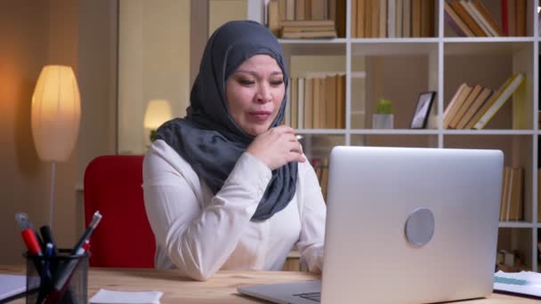 Close-up shoot van volwassen moslim zakenvrouw geeuwen en slaperig terwijl het typen op de laptop op de werkplek binnenshuis — Stockvideo