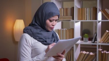 Çalışma alanında kütüphanede grafik okuyan yetişkin Müslüman iş kadını çekim çekim