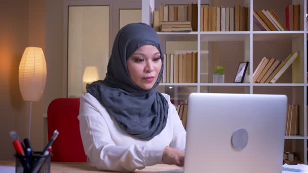 Primo piano di ripresa di adulti musulmani donna d'affari di successo digitando sul computer portatile e sorridendo con eccitazione sul posto di lavoro al chiuso — Video Stock