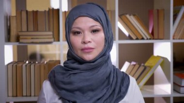 Evde çalışma alanında kütüphanede kamera ayakta bakarak yetişkin Müslüman iş kadını çekim çekim
