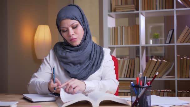 Nahaufnahme einer erwachsenen muslimischen Allgemeinmedizinerin im Hijab, die für eine medizinische Untersuchung in der Bibliothek drinnen studiert — Stockvideo