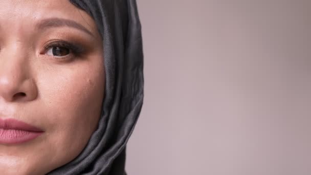 特写镜头半脸拍摄的成人有吸引力的穆斯林女性在头巾向前看, 转向相机与孤立的背景 — 图库视频影像