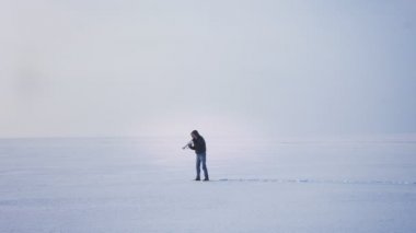 Yalnız beyaz müzisyen geniş çekim trompet onu yukarı ve aşağı dondurulmuş göl arka planda koyarak oynuyor.