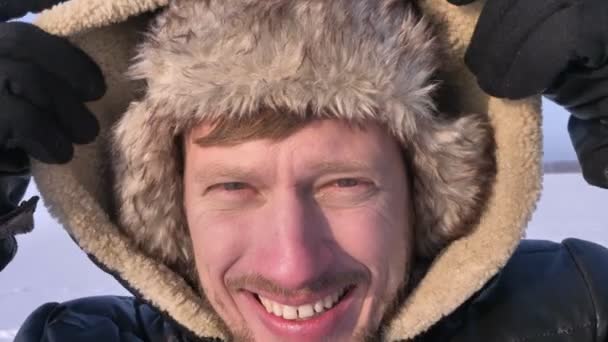 Крупный план средневекового исследователя, надевающего капюшон и спокойно смотрящего на камеру в снежной пустыне . — стоковое видео