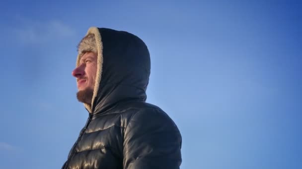 Blick auf einen Entdecker mittleren Alters mit Kapuze, der optimistisch und nachdenklich der Sonne in der Schneewüste zusieht. — Stockvideo