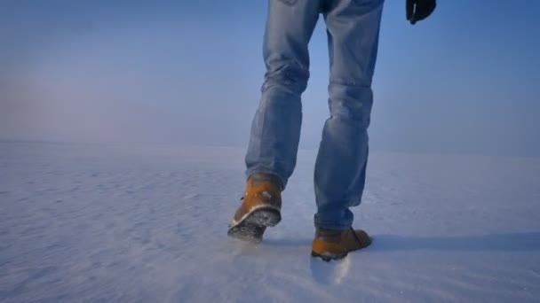 Krąży wokół widoku od dołu do góry człowieka spaceru wokół pola śniegu. — Wideo stockowe
