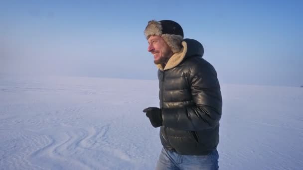 Profiel portret van Running Man in bont hoed en warme vacht op sneeuwveld. — Stockvideo