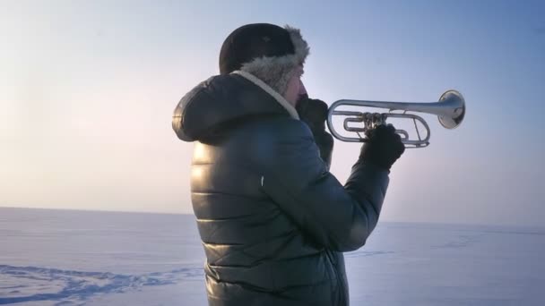 Rodeando alrededor de tiro de mediana edad músico caucásico tocando trompeta activamente en el fondo de la naturaleza de invierno . — Vídeo de stock