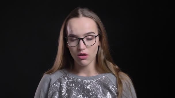 Close-up opnamen van jonge aantrekkelijke hipster vrouw in glazen met een zieke keel en ziek met geïsoleerd op zwarte achtergrond — Stockvideo