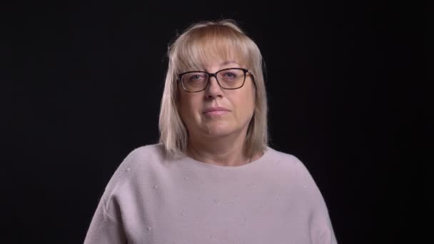 Closeup shoot of old aucasian blonde female in glasses getting excited and joyful in front of the camera with background isolated on black — Stock Video