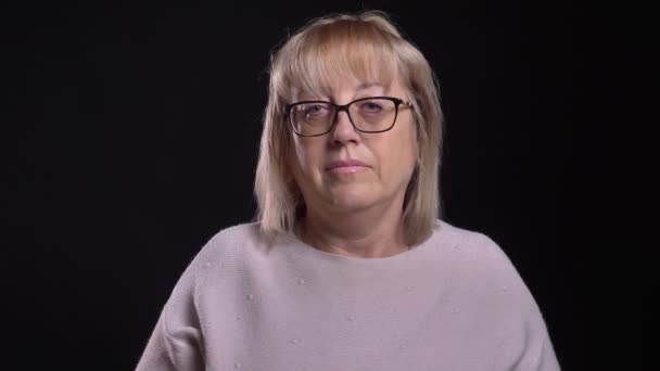 Closeup shoot of old caucasian blonde female in glasses having a sick throat and coughing in front of the camera with background isolated on black — Stock Video