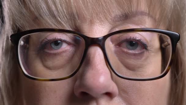 Съемки крупным планом старой белокурой женщины в очках с глазами, смотрящими прямо в камеру — стоковое видео