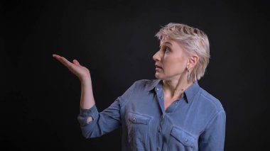 Tatlı yetişkin çekici beyaz kadın eliyle işaret üstünde belgili tanımlık yan sunuyu gösteren portresi