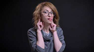 Orta yaşlı abartılı Kızıl saçlı erkek komik bir yüz ifadesi yapma ve neşeyle bir dil gösteren gözlük closeup portresi