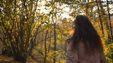 Güzel kıvırcık saçlı beyaz kız sersem sonbahar Park'ta yürüyordunuz arka portresi.