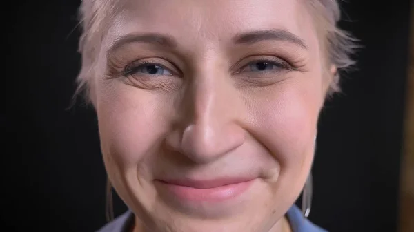 Closeup πυροβολούν από νέους ελκυστικές καυκάσιος γυναίκα με ξανθά μαλλιά και μπλε μάτια κοιτώντας ευθεία σε φωτογραφική μηχανή με χαμογελαστό έκφραση του προσώπου — Φωτογραφία Αρχείου