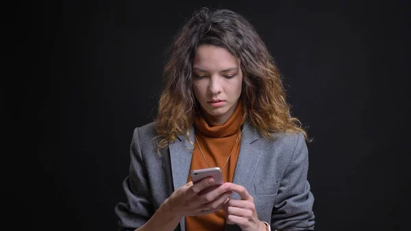 Nahaufnahme von jungen attraktiven kaukasischen Frau mit dem Telefon vor der Kamera mit Hintergrund isoliert auf schwarz — Stockfoto