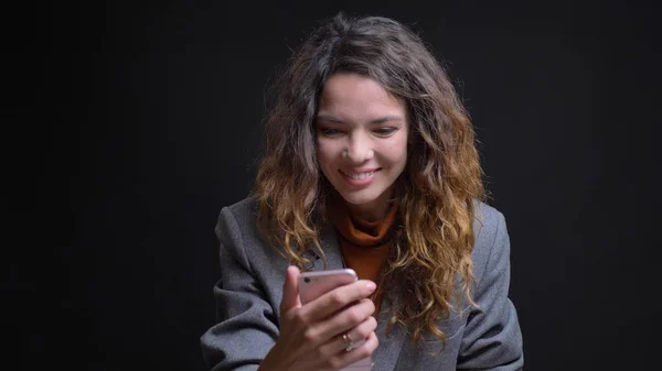 Closeup shoot of young attractive caucasian female having a video call on the phone cheerfully smiling in front of the camera — Stock Photo, Image