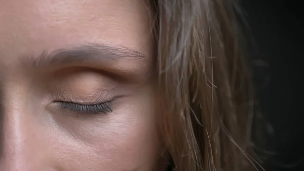 Closeup half-face shoot of young pretty caucasian brunette female face with brown eye being closed in front of the camera — Stock Photo, Image