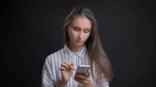 Крупним планом портрет молодої милої білої жінки, використовуючи телефон перед камерою з ізольованим фоном — стокове фото